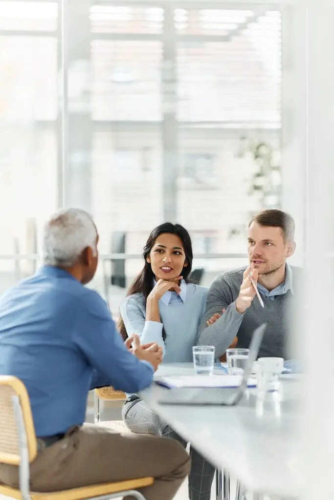 Diverse couple communicating with their agent during a meeting in the office. The view is through glass.
