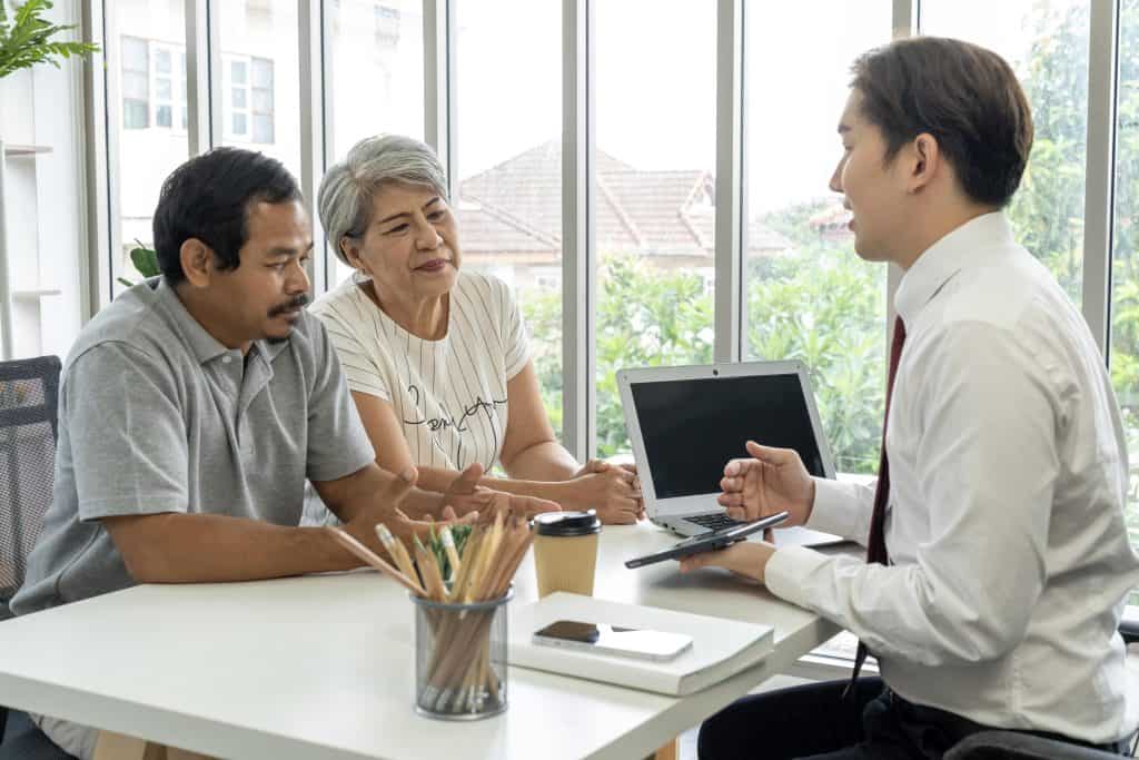 Asian young employee is offering about life insurance plan to aged couple stock photo