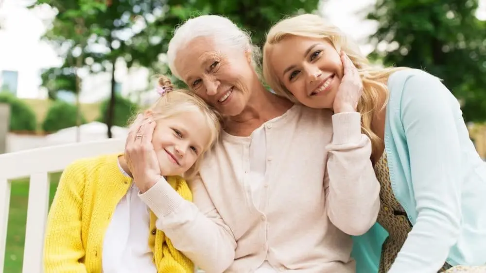 family, generation and people concept - happy smiling woman with daughter and senior mother sitting on park bench